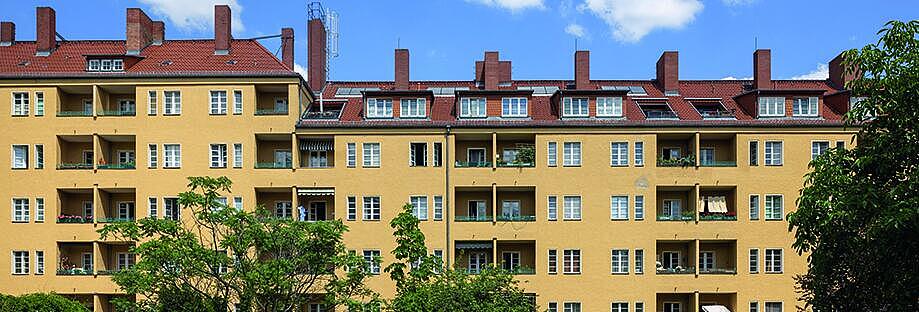 Außenaufnahme zeigt die rückwärtige, gelb gestrichene Fassade mit Balkonen und ausgebauten Dachwohnungen eines Wohnblocks in der Afrikanischen Straße im Wedding. 