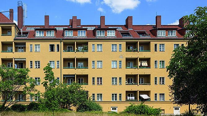 Außenaufnahme zeigt die rückwärtige, gelb gestrichene Fassade mit Balkonen und ausgebauten Dachwohnungen eines Wohnblocks in der Afrikanischen Straße im Wedding. 